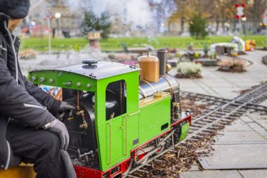 Kış boyunca parkta küçük yeşil buhar treni. Şenlikli aile gezisi kavramı, tatil ulaşımı