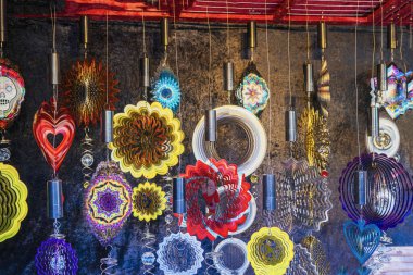 Markette asılı renkli metal rüzgar fırıldakları. Canlı tatil süslemeleri ve sanatsal açık hava süslemeleri kavramı