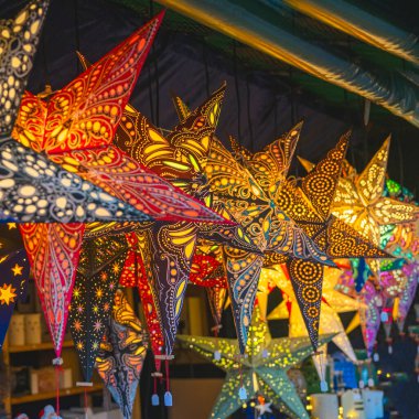 Değişik renklerde parlayan renkli ışıklı dekoratif yıldızlar, akşamları festival pazarı, canlı bir arka plan.