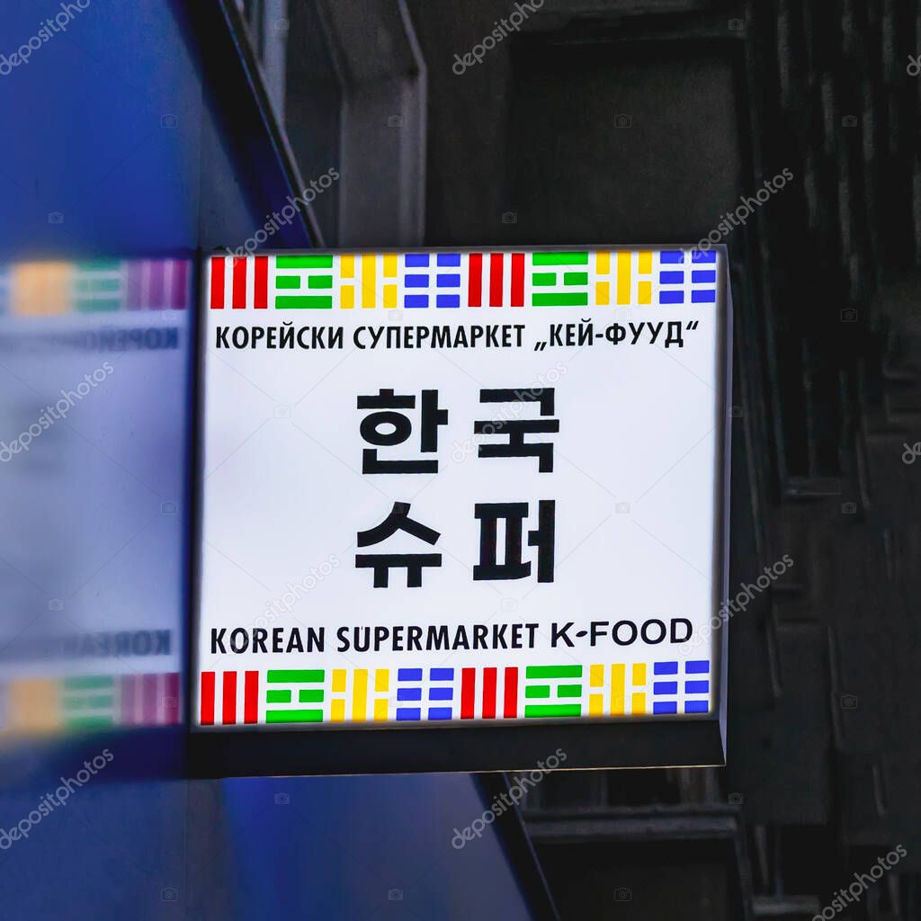 Korean supermarket sign with bold black letters and colorful traditional Korean symbols at night in Burgas, Bulgaria. Korean supermarket visual communicates culture, food, and identity