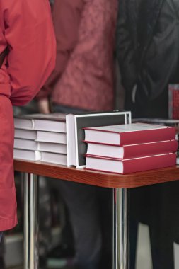 Kitap fuarında ya da etkinlikte kırmızı kapaklı kitaplar ahşap masaya düzgünce istiflenir. Yayımcılık ve okuyucu ilgisi odaklı kitap tanıtım kavramı