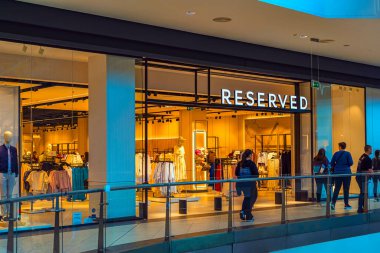 Mankenler, giyim mağazaları ve alışveriş merkezlerindeki cam cepheden görülebilen parlak markalarla donatılmış bir moda mağazası. RESERVED perakende kavramı, çağdaş moda, marka kimliği
