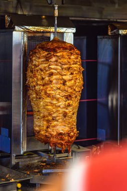 Shawarma ızgara makinesinde dönen tükürük üzerinde dikey kızarmış et yığını. Sokak yemeği kavramı, geleneksel mutfak ve otantik tadı olan fast food hazırlama.