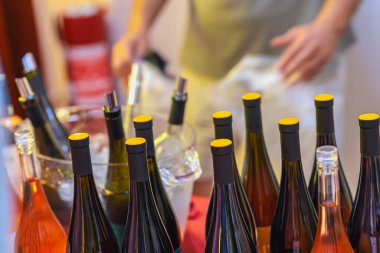 Halka açık bir etkinlikte buzluğa yerleştirilmiş sarı şapkalı çeşitli şarap şişeleri. Soğuk şarap tatma, organize bar, sosyal toplantı, parti kavramı.