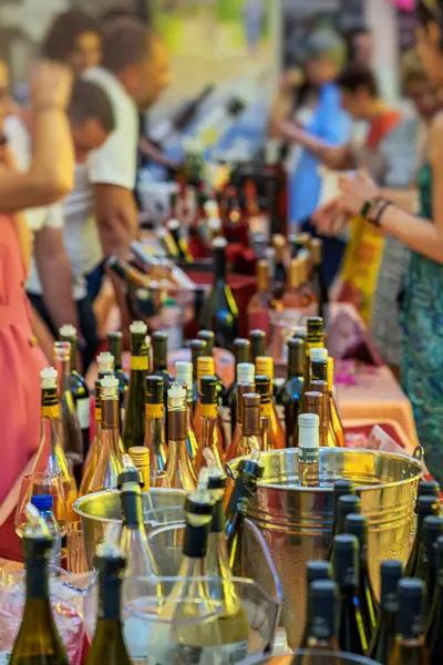 Şarap Festivali. İnsanlar çeşitli şişe ve buz kovalarıyla dolu şarap tatma festivali masasında toplandılar. Kutlama kavramı, halka açık etkinlik, şarap partisi