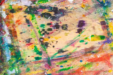 Messy wooden artist palette covered in vivid paint splashes, brush marks, colorful smudges from creative process. Concept of painting, artistic expression, vibrant studio chaos. Natural art background