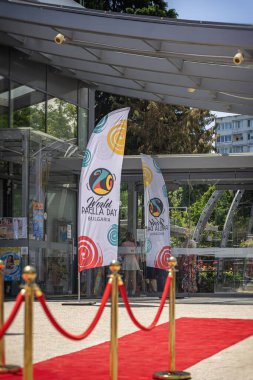 Bulgaristan 'ın Burgaz kentinde düzenlenen Dünya Paella Günü festivaline kırmızı halıyla giriş, aşçılık kutlamalarına konukları karşılayan bayraklar. Olay kavramı, gıda kültürü, tüm ziyaretçiler için şenlikli atmosfer