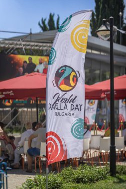 Bulgaristan 'ın Burgaz kentinde Dünya Paella Günü' nü düzenleyen renkli desenli bayrak, yaz festivalinde açık havada sergilendi. Kutlama anlayışı, aşçılık kültürü, şenlikli halk toplantısı