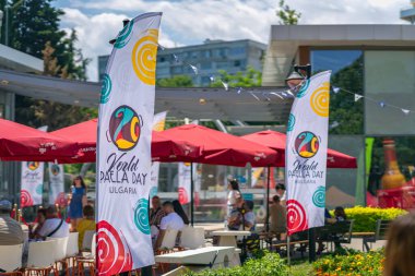 Bulgaristan 'ın Burgaz kentinde düzenlenen Dünya Paella Günü' nde renkli bayraklar ve açık hava oturma alanları, şenlikli dekorasyonlar. Yemek festivali kavramı. İspanyol kültürü günleri, otantik İspanyol mutfağı. Sole Festivali