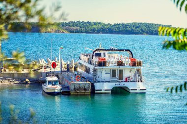 Yolcu feribotu Burgaz, Bulgar bayrağı ve sakin mavi denizde sakin bir marinaya yanaştı. Ulaşım kavramı, yaz yolculuğu, huzurlu kıyı yaşamı, deniz yolculuğu.
