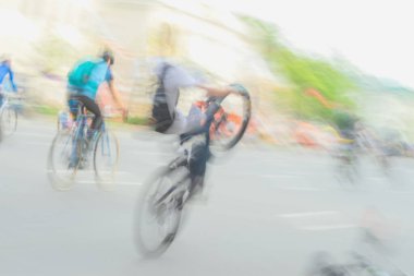 Şehir caddesinde dinamik hareket bulanıklığıyla numaralar yapan bir grup bisikletçi. Kentsel bisiklet kavramı, özgürlük, spor adrenalini. Hafif spor arka planı