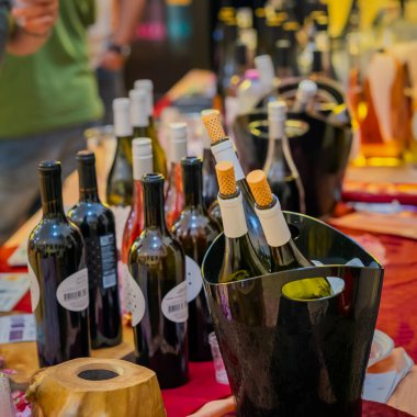 Buz kovasında şişe şarabın yakın çekimi. Şık kovada şarap şişeleri ve arkalarda bulanık kalabalıkla tatma etkinliği masasında düzgünce düzenlenmiş. Şarap sunumu konsepti, kutlama, klas tatma.