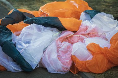 Paraglider kanadı yerde. Renkli paraglider kanadı, malzeme ve detay sergiliyor. Paraşüt Arkaplanı. Spor malzemesi konsepti, iniş sonrası anı