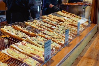 Pizza vitrini. Eritilmiş peynirle kaplı fırında baget pizzalar ve fırın tezgahında sergilenen çeşitli malzemeler. Fast food kavramı, ucuz lezzetler, sokak atıştırmalıkları.