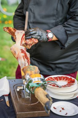 Jamon Yakın plan Dilimleme. Siyah eldivenli şef, İspanyol jamonunu ince ince dilimliyor, mermer et ve kurgu sergiliyor. Jamon dilimleme, et kesme, mutfak işçiliği kavramı.