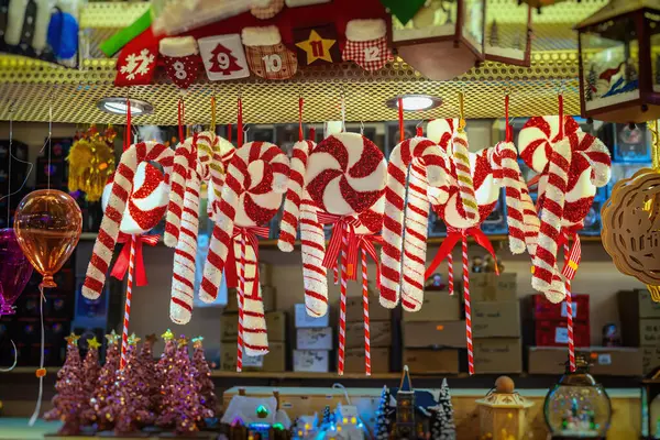 Şeker kamışı süslemeleri. Parlak kırmızı ve beyaz baston şeker süslemeleri. Parıltı ve kurdeleler bayram tezgahında asılı. Şeker kamışı kavramı, Noel tatlısı, neşeli kutlama