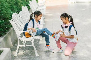 Two little girls sitting on the bench in the park