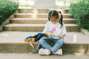 Parktaki merdivenlerde dijital tablet kullanan tatlı Asyalı kız..