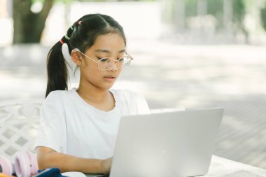 Parkta otururken dizüstü bilgisayar kullanan Asyalı genç kızın portresi.