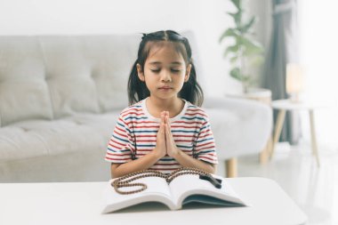 Küçük kız sabahları dua ediyor. Küçük Asyalı kız el dua ediyor. Elleri inanç, maneviyat ve din için dua kavramında katlanmış..