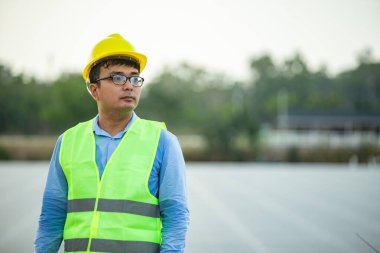 Güneş panelleriyle ekolojik yeşil alanda çalışırken zevkle gülümseyen profesyonel insan mühendisi. Fotovoltaik enerji santrali kavramı