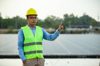 Güneş panelleriyle ekolojik yeşil alanda çalışırken zevkle gülümseyen profesyonel insan mühendisi. Fotovoltaik enerji santrali kavramı