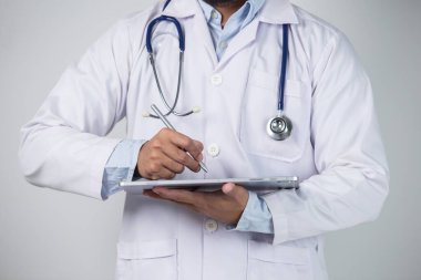 Gri arkaplanda dijital tablet kullanan bir erkek doktorun yakın çekimi