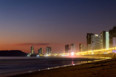 Mazatlan sinaloa plajı. Geceleri arka planda parlak bir şehir var.