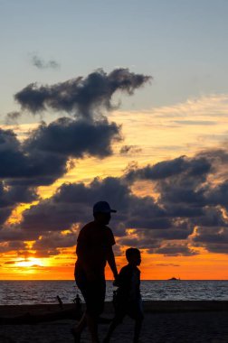 A Silhouette of little brothers playing on the beach in sunset