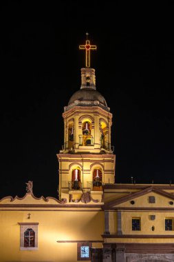 Queretaro, Meksika 'da aydınlatılmış tarihi yerleri keşfet. Kilise, gece gökyüzü altında karmaşık mimari ve kültürel önem sunar.