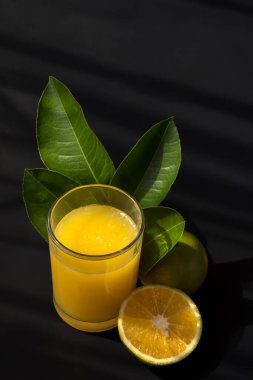 Bir portakal suyu, yapraklar ve üzerinde yazı için siyah arkaplan ve boşluk olan meyveler.