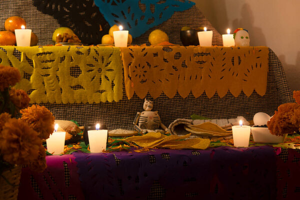 A Day of the Dead altar with skeleton, cempasuchil flowers, fruit and papel picado