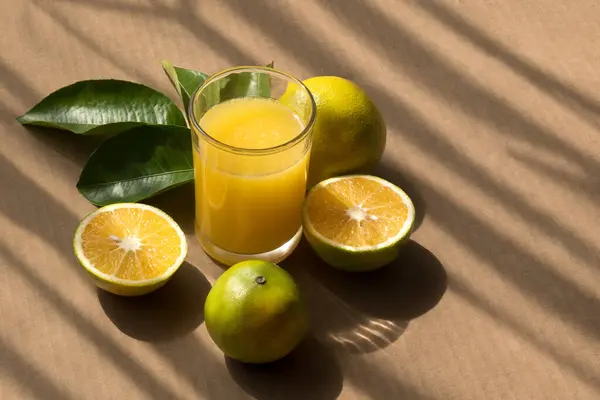 A Fresh orange juice with green leaves, whole fruit and relaxing background