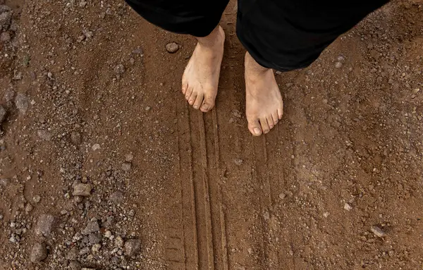 A Bare feet walking on a dirt road in the countryside