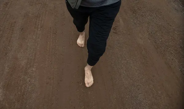 A Person with bare feet walking on dirt floor in nature