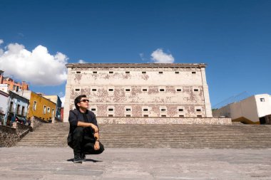 Guanajuato, Meksika 'da Alhondiga de Granaditas yakınlarında bulutlu bir gökyüzünün altında seyahat deneyiminin tadını çıkaran bir adam.