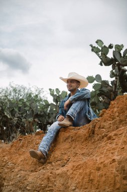 A cowboy under the vast sky, surrounded by cacti, working on a farm clipart