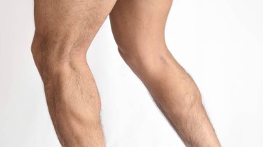 Bir adamın kaslı bacakları, iki bacağı yandan görünen baldırları, beyaz bir arka plan ve metin için boşluk.