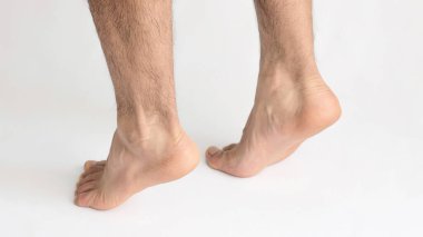 Achilles tendonunda gerilme olduğunu gösteren parmak uçlarında duran beyaz bir erkek.