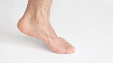 Yetişkin bir adam ayak bileğinden görünüyor, parmak uçlarında duruyor, sol ayağı yazı için, beyaz arka plan, tam ayak