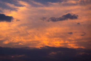 Canlı turuncu ve mor renkli, nefes kesici günbatımı gökyüzü, aydınlık bulutlar dramatik ve sakin bir akşam sahnesi yaratıyor. Doğa aşıkları ve manzara meraklıları için mükemmel. Barışçıl ve güzel gökyüzü görüntüleri arıyorlar..