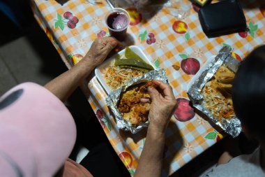 Otantik Meksika taco sudadolarının yanında canlı bir marul, havuç ve turşu salatası. Renkli bir masa örtüsünün üzerinde servis edilir, Meksika mutfağının özünü yakalar. Yemek severler ve aşçılar için mükemmel..