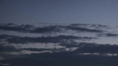 Alacakaranlıkta gökyüzünün nefes kesici dönüşümüne tanık olun. Bulutlar sürükleniyor ve şekil değiştiriyor. Bu güzel ekran, atmosferin zengin renklerini ve dokularını vurgulayarak, günden geceye geçişi yakalıyor..