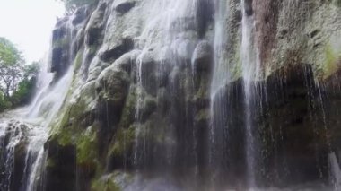 Su çarpıcı bir şelaleden zarif bir şekilde akar ve çevreleyen yeşillikler arasında sakin bir atmosfer yaratır. Damlacıklar ışıkta parıldarken akan suyun sesi havayı doldurur..