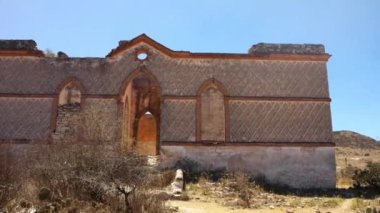 Uzak bir çöl manzarasında, berrak mavi gökyüzünün altında antik kalıntıları keşfediyor.