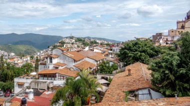 Taxco de Alarcon 'dan bu büyüleyici sahne beyaz yıkanmış binalar ve terracotta çatılarıyla süslenmiş büyüleyici bir manzarayı gözler önüne seriyor. Kasaba yuvarlanan yeşil tepelerin arasına kurulmuş. Canlı bitki örtüsü cazibesini artırıyor..