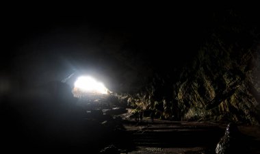 Park Nacional Grutas de Cacahuamilpa 'ya ışık yağar ve mağara içindeki karmaşık kaya oluşumlarını aydınlatır. Ziyaretçiler, karanlık ve parlak ışınlar arasındaki zıtlığı gösteren yeraltı ortamının doğal güzelliğini keşfediyorlar..