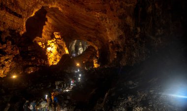 Ziyaretçiler Grutas de Cacahuamilpa Ulusal Parkı 'nın nefes kesen mağaralarında, etkileyici kaya oluşumlarına ve ışık ve gölge etkileşimlerine hayret ederek geziniyorlar..