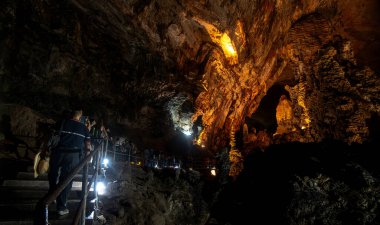 Ziyaretçiler, yumuşak ışıklandırmayla aydınlatılan etkileyici kaya oluşumlarına hayret ederek, nefes kesici Park Nacional Grutas de Cacahuamilpa içinde dolambaçlı adımlarda ilerliyorlar. Atmosfer sakin ama insanlar naanın tadını çıkarırken heyecan dolu.