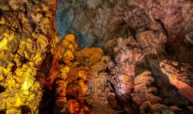 Ziyaretçiler, Grutas de Cacahuamilpa Ulusal Parkı 'nın renkli kaya oluşumlarının ve sarkıtların yapay aydınlatmayı yansıttığı nefes kesici mağaralarında geziniyorlar. Manzara, doğanın güzelliğini karmaşık tasarımları ve dokuları ile sergiliyor.